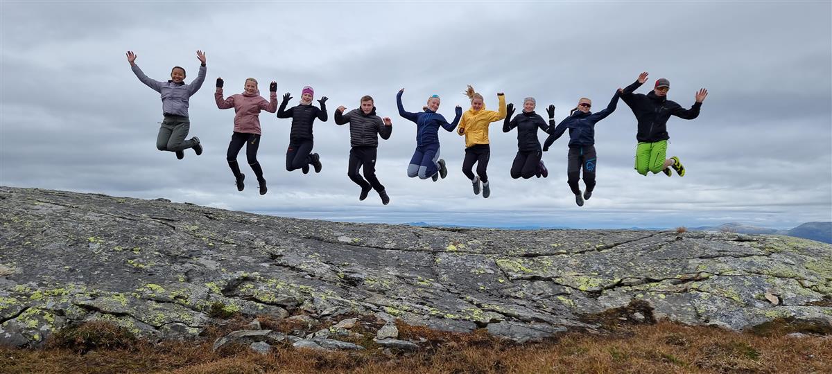 9 elever hopper i lufta på en fjelltopp. Foto. - Klikk for stort bilde
